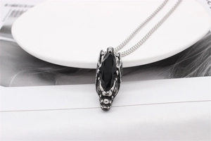 Detailed view of silver dragon head pendant with black marquise gemstone and steel chain