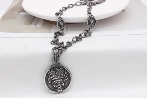 Détail d'un collier argenté vintage avec relief de crâne indien et maillons de chaîne punk