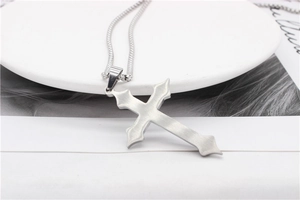 Macro shot of silver gothic cross pendant with matte brushed stainless steel finish