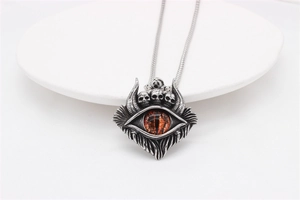 Gros plan du pendentif œil de dragon gothique avec trois crânes et une pierre rouge