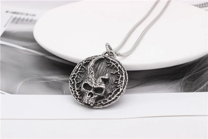 Macro shot of vintage skull round pendant with intricate embossed detailing on silver chain