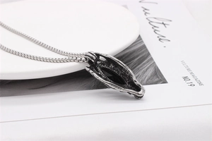 Detailed close-up of retro dragon head pendant with black gemstone on magazine background