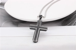 Detail of cross pendant featuring a black diamond mesh texture on a silver steel base
