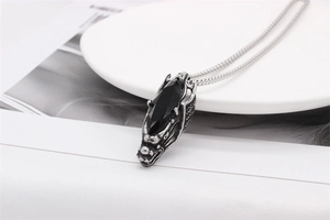 Detail of vintage silver dragon pendant with black gemstone on sleek snake chain