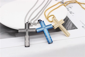 Detailed close-up of textured cross pendants in black, blue, and gold with central zircon