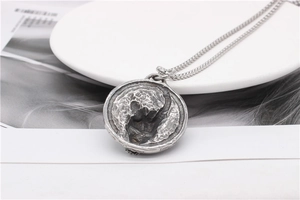 Detail of vintage silver round pendant with moon surface texture and woven metal chain