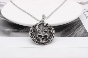 Close-up of vintage silver gothic skull pendant on stainless steel chain over props