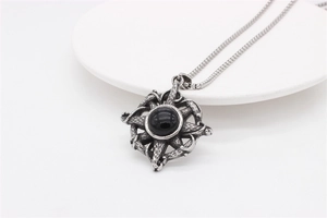 Detail of vintage silver cross pendant featuring a round black stone and textured metalwork