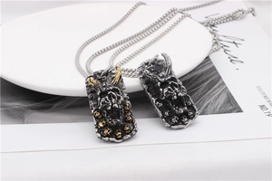 Detail of gothic stainless steel demon skull pendants in silver and black gold finishes