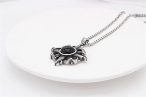 Close-up of retro cross punk pendant with black gemstone and textured stainless steel scale detail