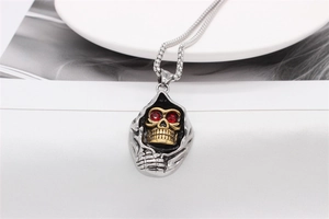 Détail du pendentif tête de mort gothique avec visage doré et yeux en pierres rouges