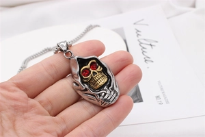 Gros plan du pendentif crâne punk avec yeux en gemme rouge et texture en acier argent