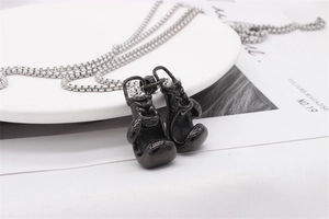 Detail of black boxing glove pendant with silver box chain on ceramic tray