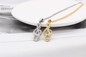 Detail of gold and silver treble clef musical note pendants on minimalist link chains