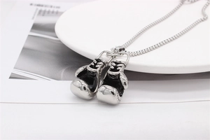 Macro detail of polished stainless steel boxing glove pendants with intricate lace carvings