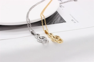Close-up of gold and silver music note necklaces on a white plate with artistic vibe
