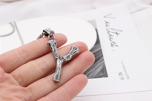 Close-up of vintage silver Y-letter pendant necklace with rustic wood grain texture