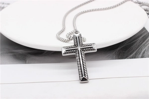 Gros plan détaillé du pendentif croix argentée avec texture de corde au style rétro