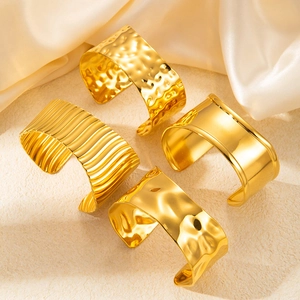 Hammered and smooth 18k gold plated stainless steel open bangles on silk background