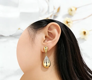 Detailed close-up of golden teardrop drop earrings featuring sparkling micro-pave crystals