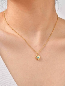 Close-up of a vintage gold heart lock necklace with blue turquoise and beaded chain detail