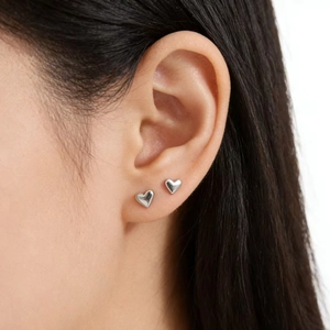 Minimalist S925 sterling silver heart stud earrings worn on female ear for a chic look