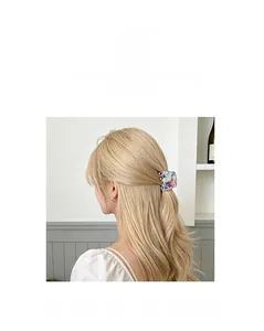 Detail of a rectangular acetate hair claw with floral patterns on blonde hair
