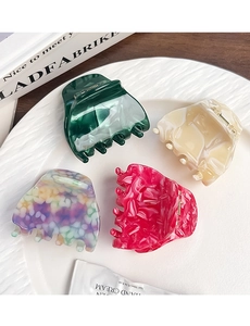 Detailed view of four acetate hair claws with marble textures on a white textured plate