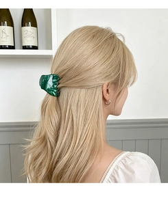 Detail of a green marble pattern acetate hair claw clip worn by a blonde model