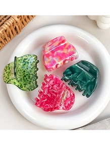 Detailed set of four acetate hair claws in floral and marble patterns on ceramic plate