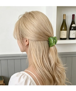 Green leopard print acetate claw clip styling on wavy hair in a chic indoor setting