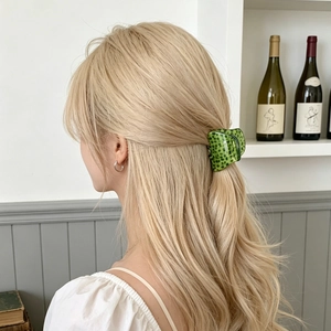 Green leopard print acetate claw clip shown on a half-up hairstyle in a lifestyle setting