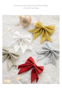 Close-up of glittery Christmas tree bows in red, gold, and silver on festive snow backdrop