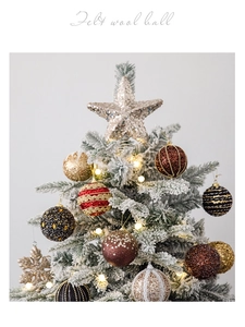 Detail of glittered Christmas balls and star topper on a snowy festive tree