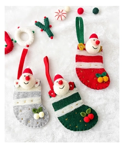 Close-up of three knitted Santa Claus Christmas stockings on a white plush background