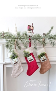 Detail view of knitted Christmas stockings with XMAS embroidery and pine branch inserts