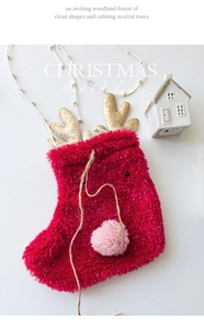 Detail of red plush Christmas stocking with gold sequin antlers and pink pom pom