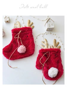 Close-up of red plush Christmas socks with gold antlers and felt wool ball decorations