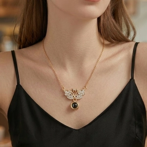 Golden necklace featuring a crystal swan pendant with a black stone on model
