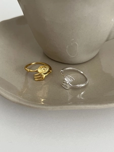 Detail of creative spoon and fork silver ring with hammered texture on a ceramic cup
