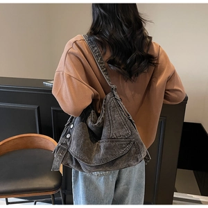 Large capacity washed black denim tote bag shown worn as a crossbody bag for style