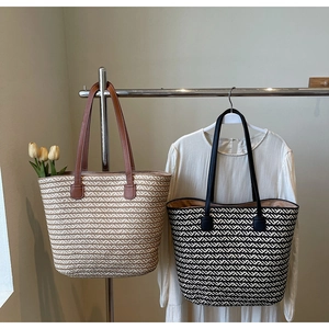 Detail view of woven striped tote bags with leather handles on a minimalist hanger