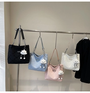Close-up of quilted tote bags in black, blue, pink, and white with plush cloud charms
