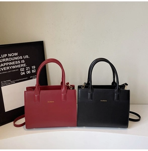 Detail view of red and black leather crossbody bags with sleek golden hardware and handles