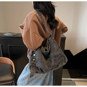 Detail of vintage gray denim tote bag shown on model in a modern room setting