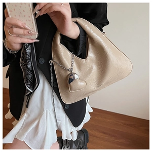 Detail of apricot pleated dumpling bag with silver heart chain and crossbody strap