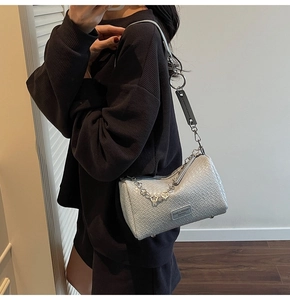 Detail of grey crossbody pillow bag featuring woven texture and silver chain handle
