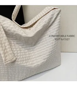 Detailed view of the soft beige striped cotton fabric texture on a large tote bag