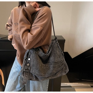 Detail of vintage washed denim tote bag with metallic buttons and flap structure