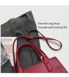 Detailed view of red tote bag with gold hardware set against a grey blazer and book